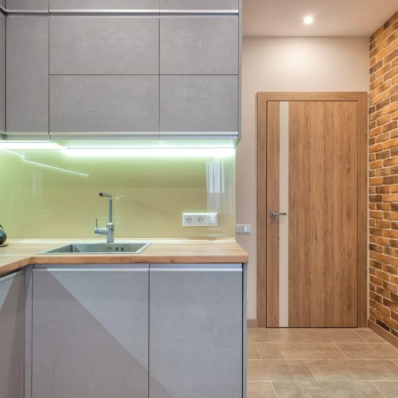 Pale green glass splashback behind a kitchen sink and timber benchtop
