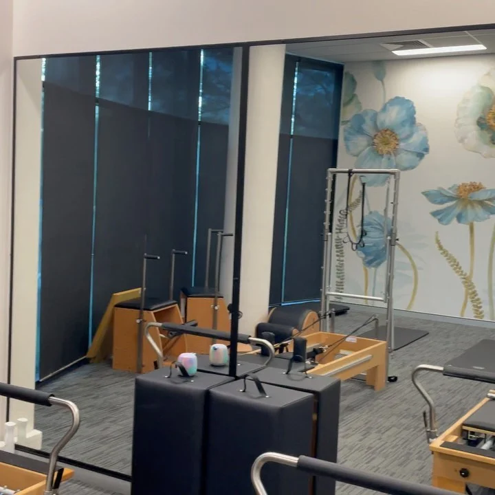 Large wall mirrors reflecting exercise equipment in a physio studio